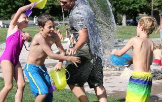 Children playing outside in water with adult staff